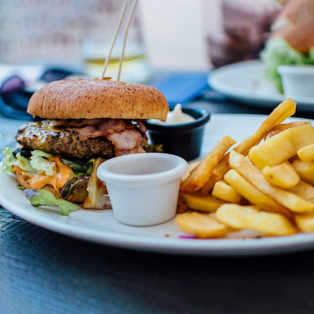 A juicy loaded burger with large fries and some sauce